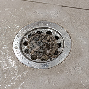 A shower drain that is clogged by a buildup of hair